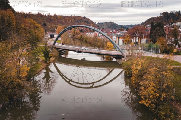 Rustic bridge over a river surrounded by colorful autumn trees and a reflection of the bridge in the water, Sulz am Neckar, Germany