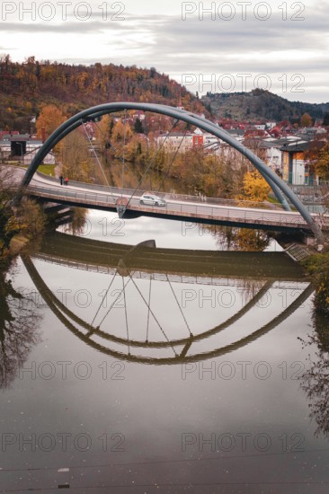 Bridge with arched design reflecting in calm river water surrounded by autumn trees, Sulz am Neckar, Germany
