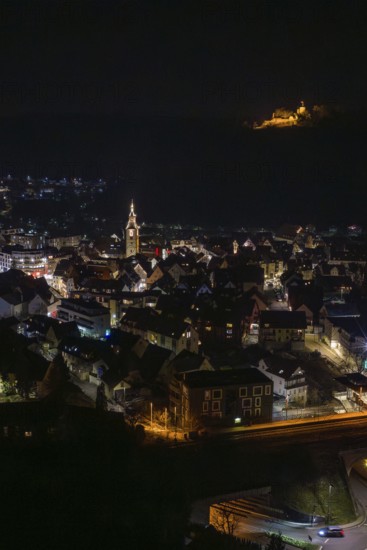 A night view of the city with illuminated church and castle on a hill in the background, Nagold, Calw district, Germany