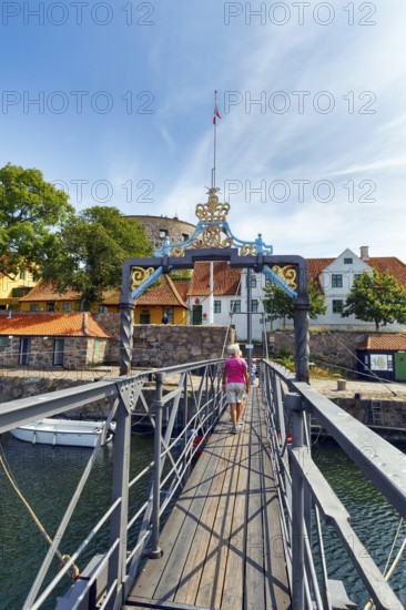 Female walker on bridge for pedestrians between ChristiansÃ¸ and FrederiksÃ¸, Christiansö and Frederiksö, Ertholmene, Pea Islands, Bornholm, Denmark