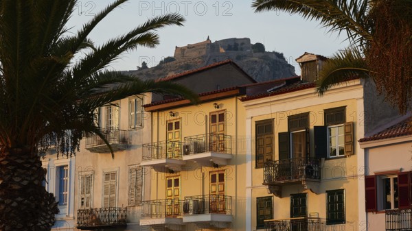 Palamidi Fortress, Old Town of Nauplion, Colourfully painted houses with a view of a fortress and palm trees in the foreground, Nauplion, Nafplion, Peloponnese, Greece