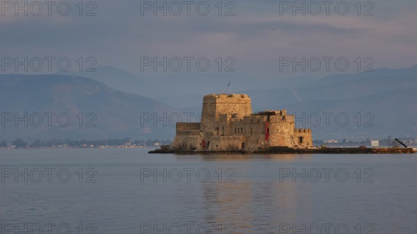 Bourtzi island fortress, a historic castle island in calm water against a mountain backdrop, Nauplion, Nafplion, Peloponnese, Greece