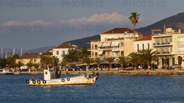 Port of Nauplion, A boat in a quiet harbor with coastal buildings and palm trees in the background, Nauplion, Nafplio, Peloponnese, Greece