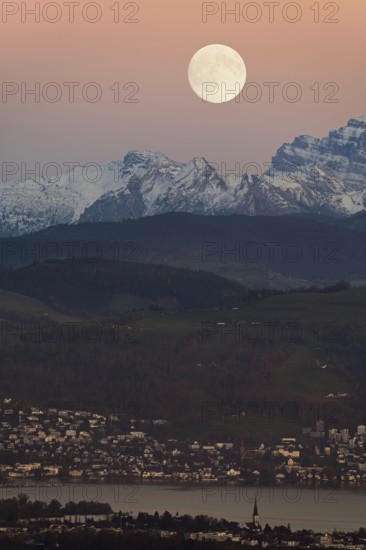 View from Horben of Lake Zug with the town of Cham and Zug, behind it the snow-capped mountains FlÃ¼brig and VrenelisgÃ¤rtli, in the light of a full moon, Beinwil-Freiamt, Canton, Aargau, Switzerland