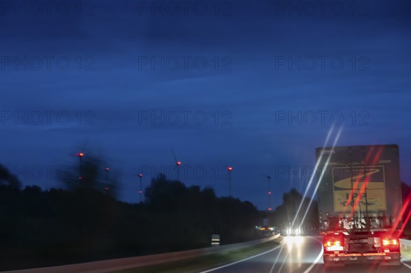 Truck on road at night, wind turbine lights on the left, Schleswig-Holstein, Germany