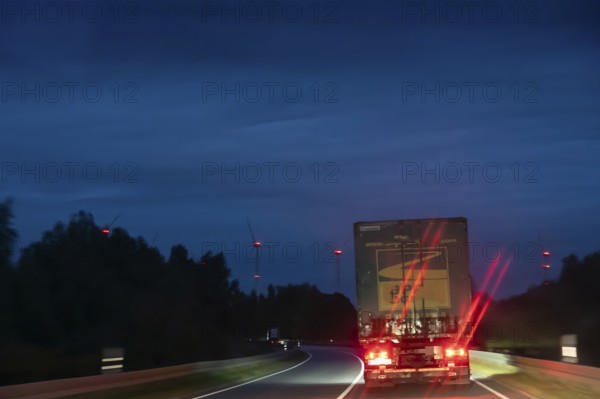Truck on federal highway at night, wind turbine lights on the left, Schleswig-Holstein, Germany