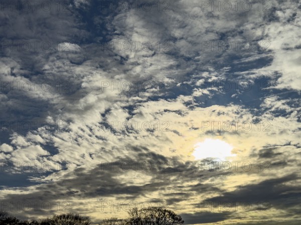 Altocumulus fractus cluster clouds in the lower half of the image Sun shines through Altostratus translucidus, international