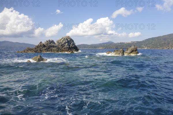 Rock reef with three rocks rising out of the sea Water above water surface Sea level off the coast of the Tuscan island of Elba in the Mediterranean, Elba, Tuscany, Italy