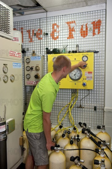 Dive instructor operates compressor fills scuba tanks scuba diving equipment for recreational divers for scuba diving with compressed air, international