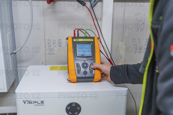 Person holds meter on a solar panel to check performance