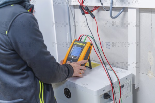 Technician checks solar system with measuring device device and cables in the device