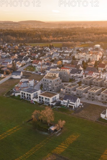 Village with modern buildings surrounded by fields in the evening light, Althengstett, Calw district, Germany