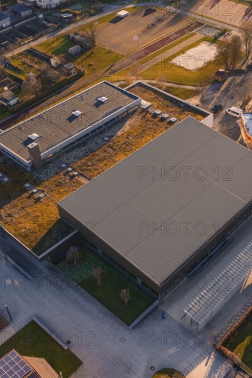 Sports center and swimming pool with flat roof and adjacent parking lot, surrounded by green areas and city limits, Althengstett, Calw district, Germany