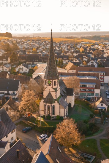 Bird's eye view of a village with a church in the center, surrounded by blooming trees and houses in the evening light, Althengstett, Calw district, Germany