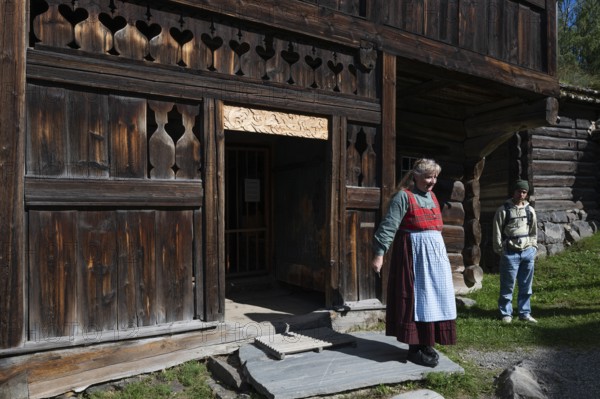 Tourist guide in traditional traditional costume and visitor, BjÃ¸rnstad, farm from VÃ¥gÃ¥, Maihaugen open-air museum with houses and objects from farms in Gudbrandsdal, Lillehammer am MjÃ¸sa Lake, Fylke Innlandet Municipality, Norway