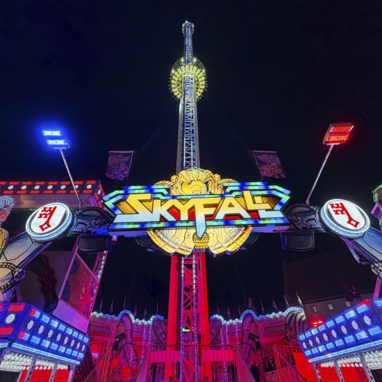 Colourfully illuminated Skyfal free fall tower at night at the All Saints Fair, Soest, North Rhine-Westphalia, Germany