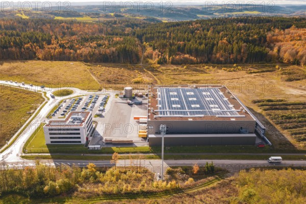 Large factory with parking lot, surrounded by forest and open spaces in an autumnal setting, new Lindenrain industrial park, Calw, Black Forest, Germany