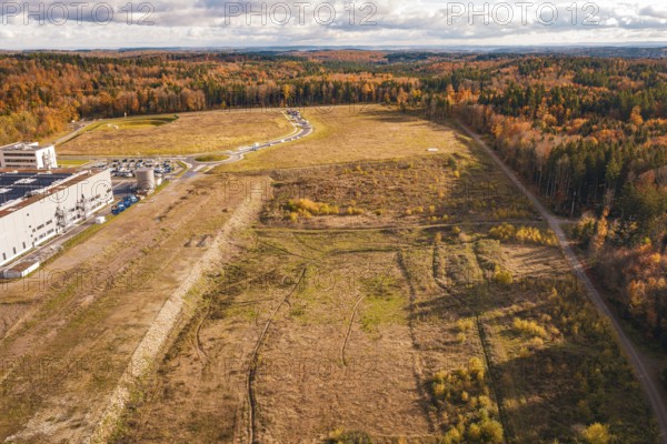 Wide, empty area next to sparse forest and industrial plant in an autumnal setting, new Lindenrain industrial park, Calw, Black Forest, Germany