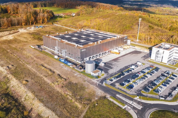 Building with a large parking lot in a hilly landscape, surrounded by autumn colors, new Lindenrain industrial park, Calw, Black Forest, Germany