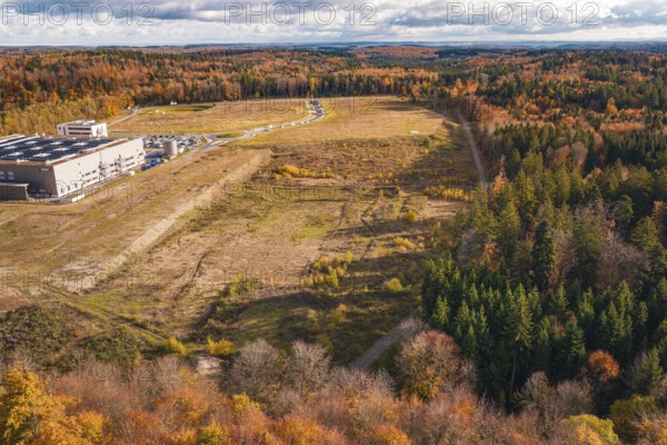 Industrial plant in autumn, surrounded by diverse forest in an open landscape, new Lindenrain industrial park, Calw, Black Forest, Germany