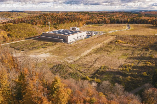 Aerial view of an industrial building surrounded by autumn forest and open fields, new Lindenrain industrial park, Calw, Black Forest, Germany