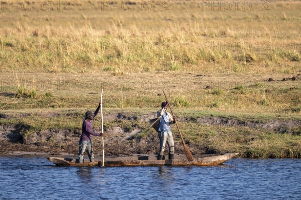 Locals with dugout boat in Chobe River, Ihaha, Chobe National Park, Botswana