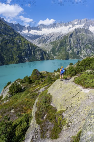 Female mountaineer in front of picturesque mountain landscape, turquoise-blue mountain lake Göscheneralpsee, Dammastock and Damma glacier, Göscheneralp, Canton of Uri, Switzerland