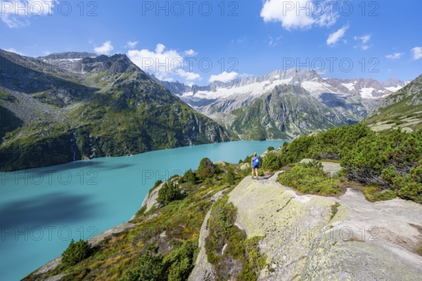 Female mountaineer in front of picturesque mountain landscape, turquoise-blue mountain lake Göscheneralpsee, Dammastock and Damma glacier, Göscheneralp, Canton of Uri, Switzerland