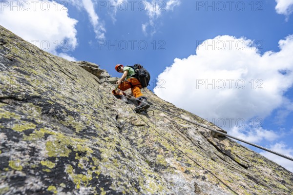 Mountaineers on steep rock face in the secured via ferrata Crocodile Mountain Lake at Bergseeschijen-Vorbau, Göscheneralp, Canton of Uri, Switzerland