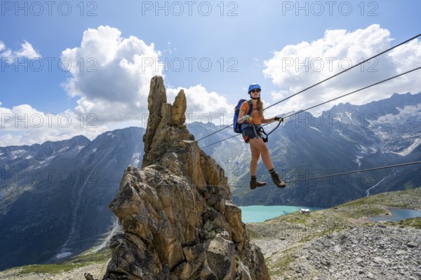 Crocodile rock formation, mountaineer on rope bridge in the Crocodile Mountain Lake via ferrata on Bergseeschijen-Vorbau, Göscheneralp, Canton of Uri, Switzerland