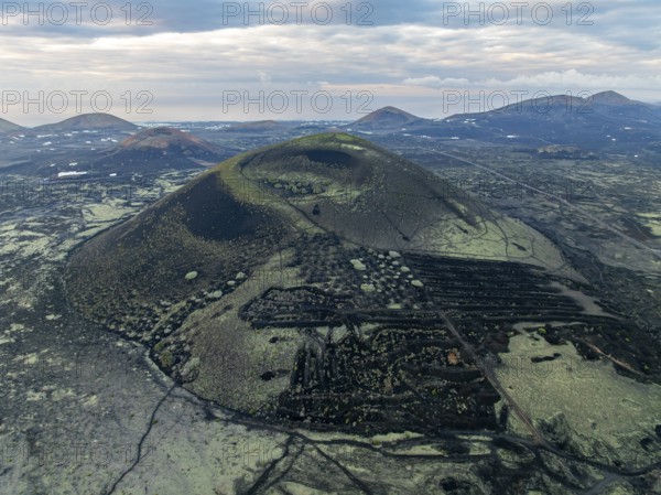 MontaÃ±a Negra volcano, picturesque volcanic landscape with volcanic crater at sunrise, Parque Natural de Los Volcanes, aerial view, Lanzarote, Canary Islands, Spain