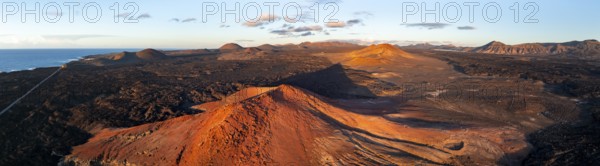 Picturesque volcanic landscape in evening light, red volcano MontaÃ±a Bermeja between lava fields, aerial view, Lanzarote, Canary Islands, Spain