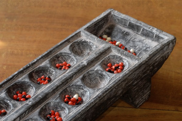 Traditional wooden game Pallankujhi, Pallamkuzhi, Pallangulli, Pallankulli or Alagulimane with red and black beans, Chettinad, Tamil Nadu, India