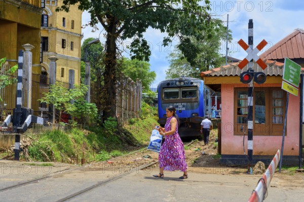 Woman crossing a railway track in front a train, Kandy, Sri Lanka
