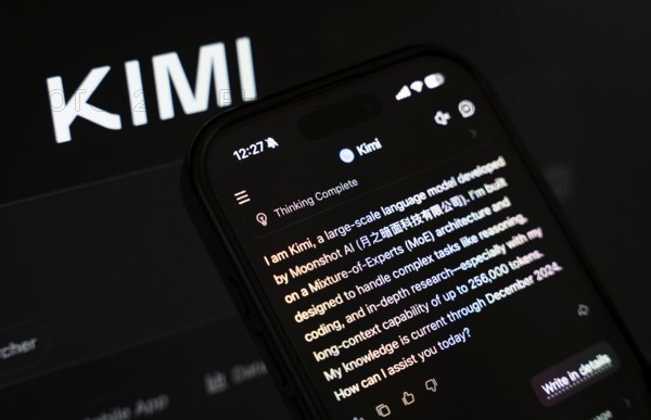 In this photo illustration, a person uses the Kimi AI chatbot on a smartphone while the KIMI logo is displayed on a screen in the background, in New Delhi, India on 20 November 2025. Kimi AI is a Chinese artificial intelligence chatbot and assistant developed by Moonshot AI, a fast-growing tech company in China