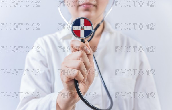 Female doctor holding stethoscope with Dominican Republic flag. National health system of Dominican Republic