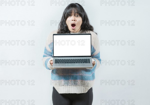 Portrait of beautiful asian girl showing laptop screen isolated. Young Asian woman displaying a promotion on laptop screen
