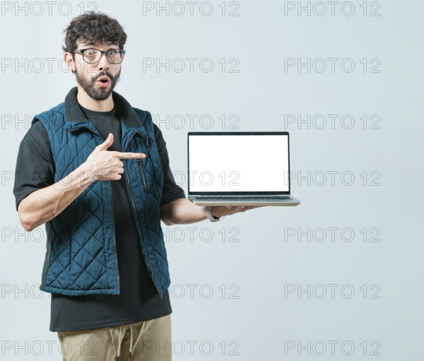 Portrait of bearded handsome man showing laptop screen isolated. Surprised Handsome Man with glasses displaying a promotion on computer screen