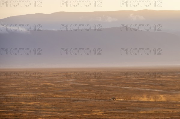 Safari vehicle, Toyota Landcruiser off-road vehicle drives in Ngorongoro Crater at sunrise, atmospheric morning light, Ngorongoro Conservation Area, Tanzania
