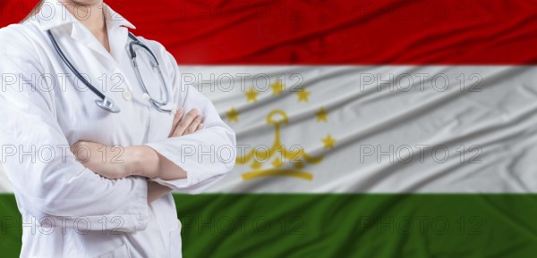 Doctor with crossed arms on Tajikistan flag. Tajikistani health and care concept. Female doctor on Tajikistan flag