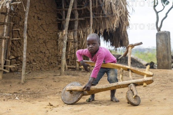 Child playing with a self-made wooden balance bike, in a Sadaani village, Tanga, Tanzania