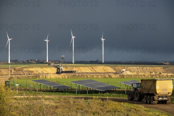 Parts of an 86.5 MW peak open-air photovoltaic system, from RWE, with over 141, 000 solar modules, on a side strip, along the A44 motorway near JÃ¼chen, on the timber triangle, recultivated open-cast mining site, in the background RWE settling in the open-cast mine, fill the pit with debris from the Garzweiler open-cast mine, JÃ¼chen wind farm, North Rhine-Westphalia, Germany