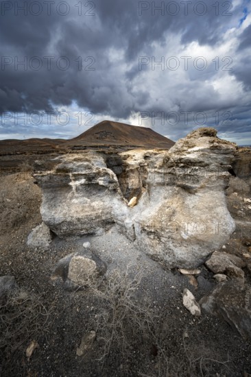 Eroded rock formations in volcanic landscape with dramatic cloudy skies, Ciudad Estratificada or Los Roferos, Antigua Rofera de Teseguite, Lanzarote, Canary Islands, Spain