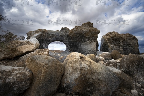 Eroded rock formations with rock tunnels, volcanic landscape with dramatic cloudy skies, Ciudad Estratificada or Los Roferos, Antigua Rofera de Teseguite, Lanzarote, Canary Islands, Spain