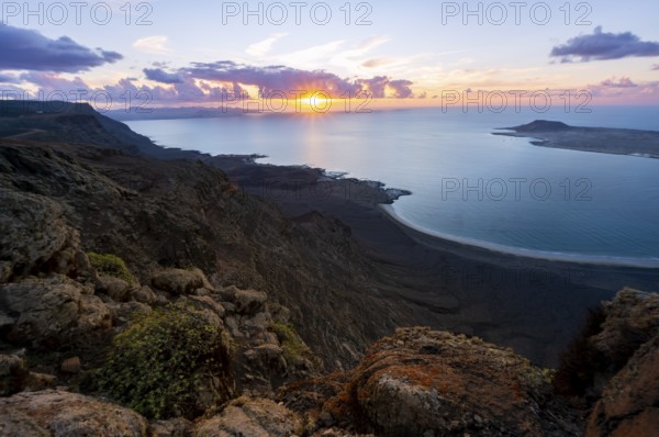 View from steep cliffs to sea and coast with sun stars, Mirador del Porrito viewpoint at sunset, Lanzarote, Canary Islands, Spain