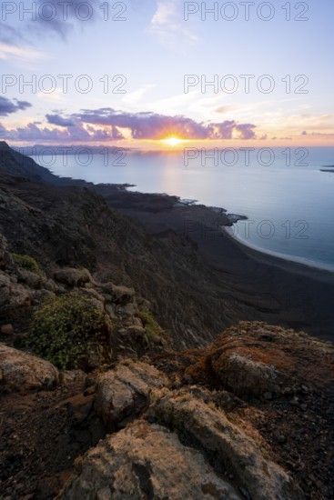View from steep cliffs to sea and coast with sun stars, Mirador del Porrito viewpoint at sunset, Lanzarote, Canary Islands, Spain