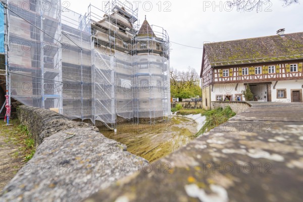 Scaffolded building, adjacent to a half-timbered house in a historic village, Wasserschloss Glatt, Sulz, Germany