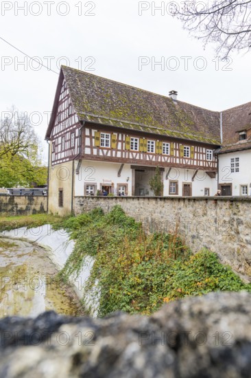 Well-preserved traditional half-timbered house next to a stone wall in a rural area, Wasserschloss Glatt, Sulz, Germany