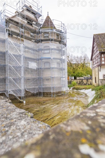 A medieval tower with scaffolding near a half-timbered house, both under renovation, Wasserschloss Glatt, Sulz, Germany