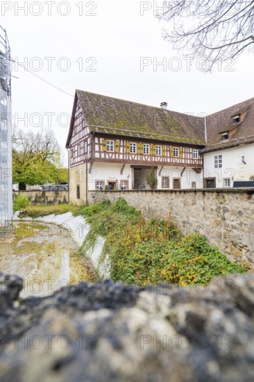 Half-timbered house with old walls and adjoining ensemble of buildings in an autumnal village landscape, Wasserschloss Glatt, Sulz, Germany